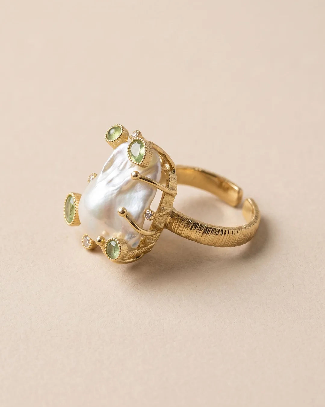 Bague Perle Baroque Pierres Vertes Dorée, packshot sur fond beige