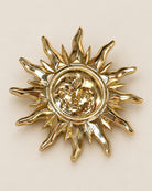 Broche Soleil Visage Doré, packshot sur fond beige