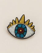 Broche Œil Brodé Doré et Bleu, packshot sur fond beige